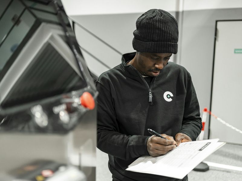 A service technician filling in a checklist beside equipment