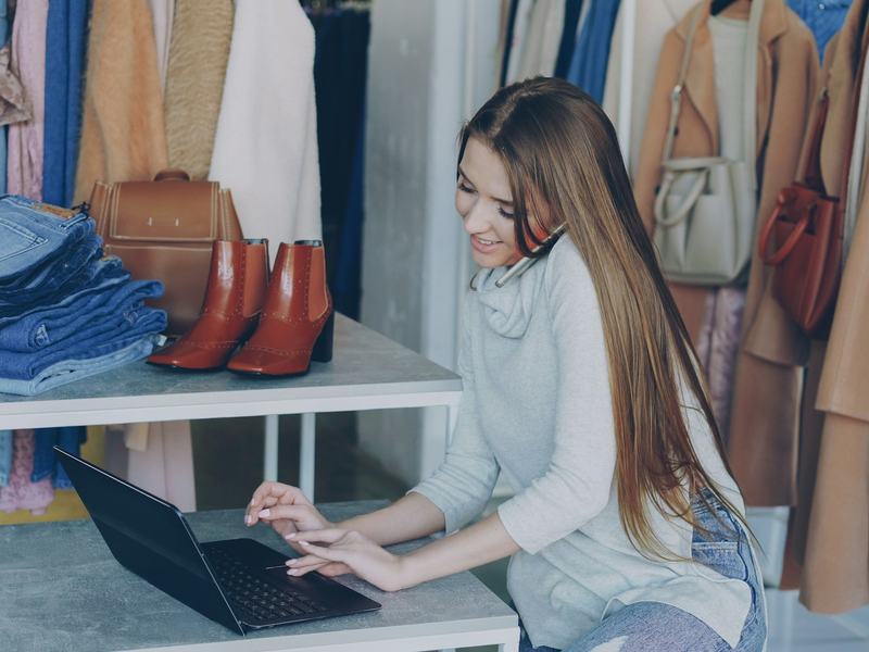A shop owner working on a laptop among her stock